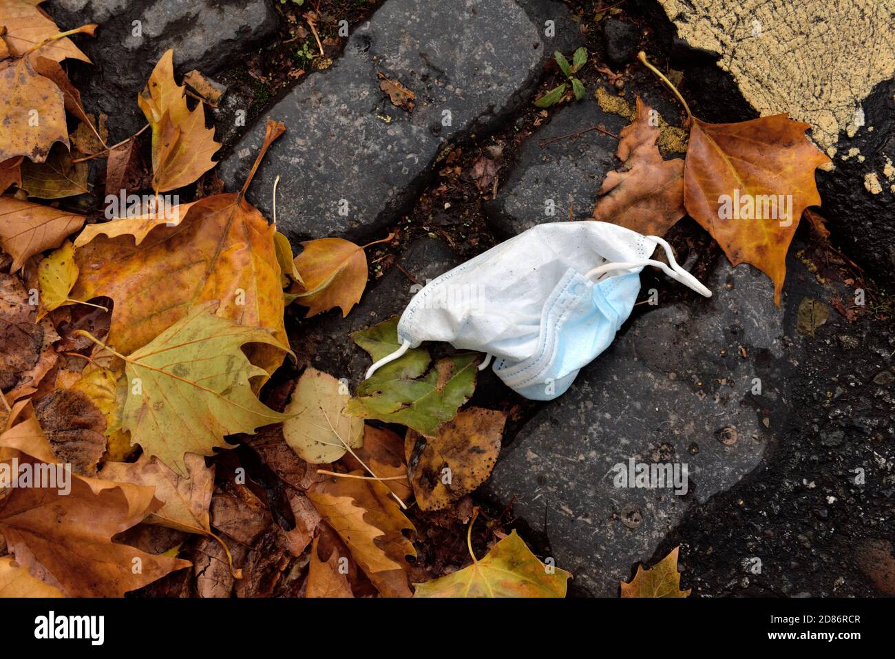 Hardly used disposable face mask for covid protection thrown away on street as litter, UK Stock Photo