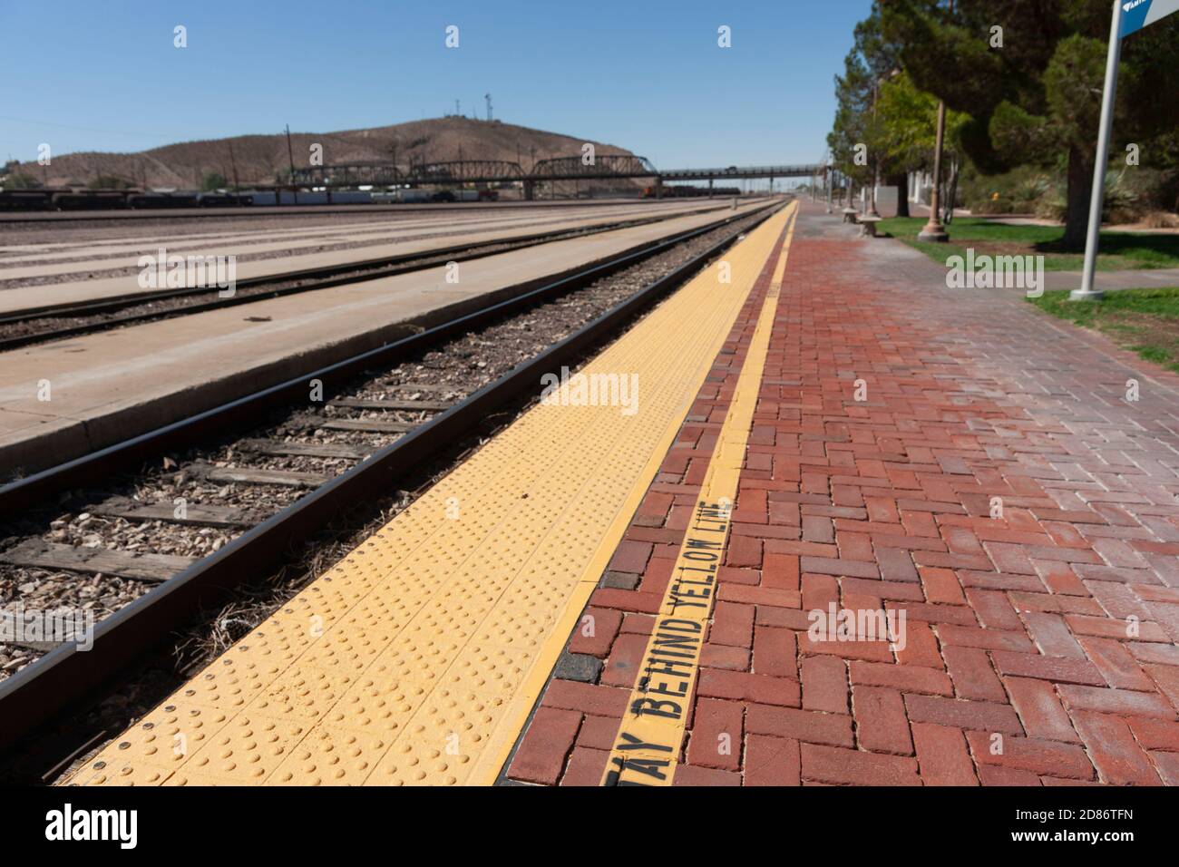 Long parralel merging train tracks and and platform converging into a blurred background. Stock Photo