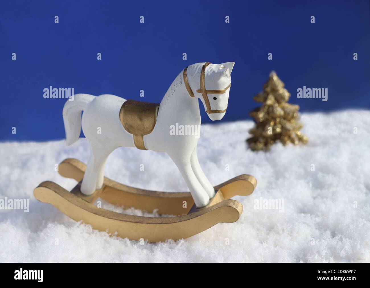christmas scene with a rocking horse on snow and a christmas tree in the back Stock Photo