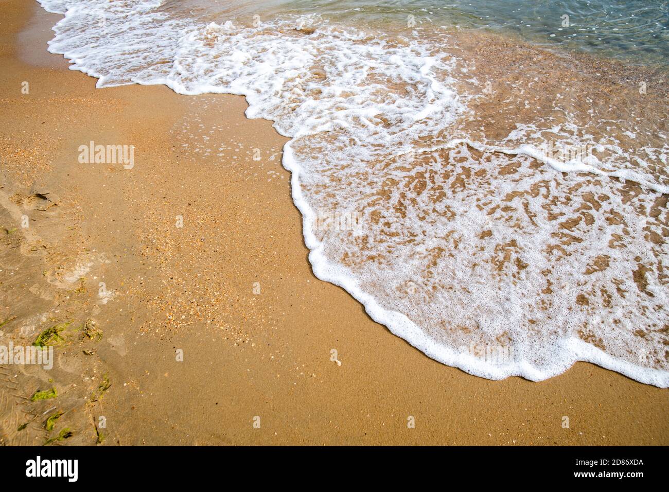 Waves with sea foam on a sandy beach Stock Photo - Alamy