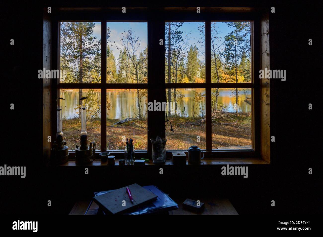 View through the window from a Swedish cabin on a lake with trees with fall colours. Stock Photo