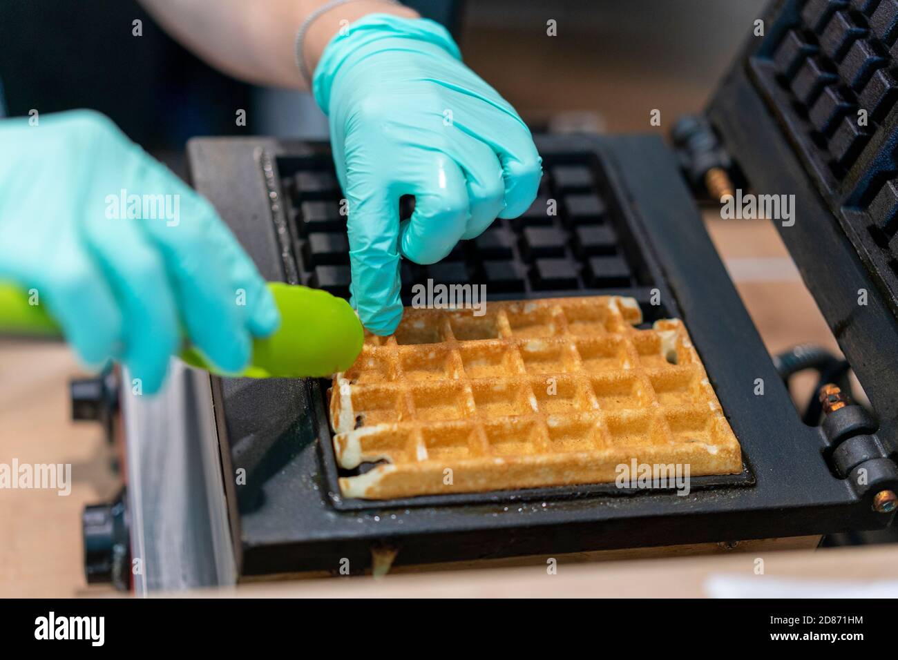 Waffle iron in the kitchen. Preparing homemade waffles, pouring a dough