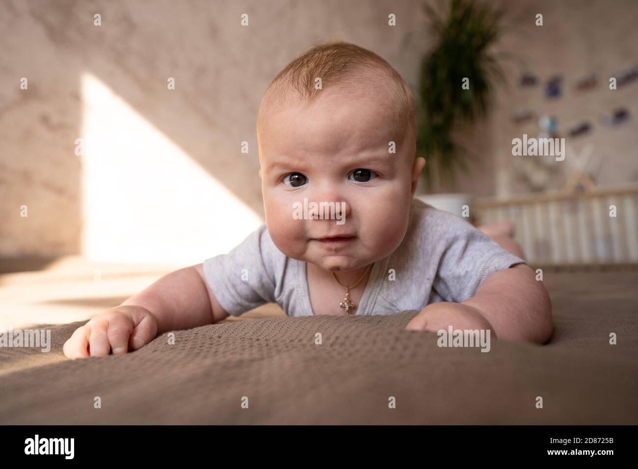 Cute three months old Baby girl infant on a bed on her belly with head