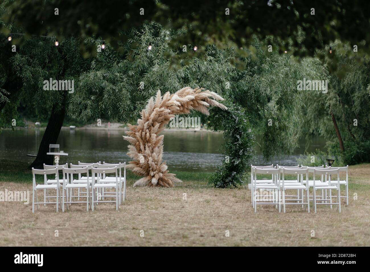 Wedding arch under the tree and chairs for guests. Outside ceremony place. Wedding arch. Wedding ceremony place Stock Photo