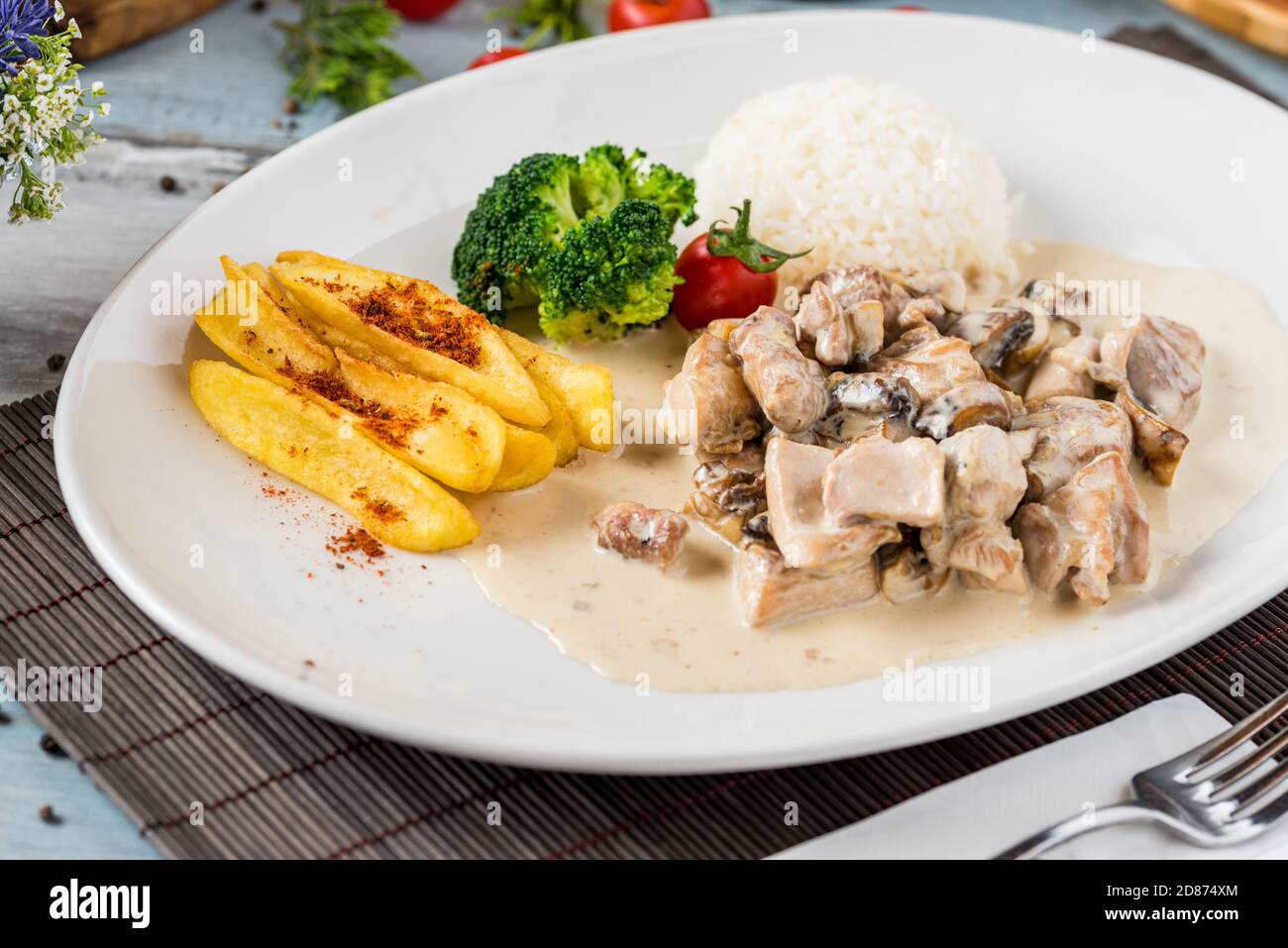 grilled chicken with rice and fried potatoes on white plate Stock Photo