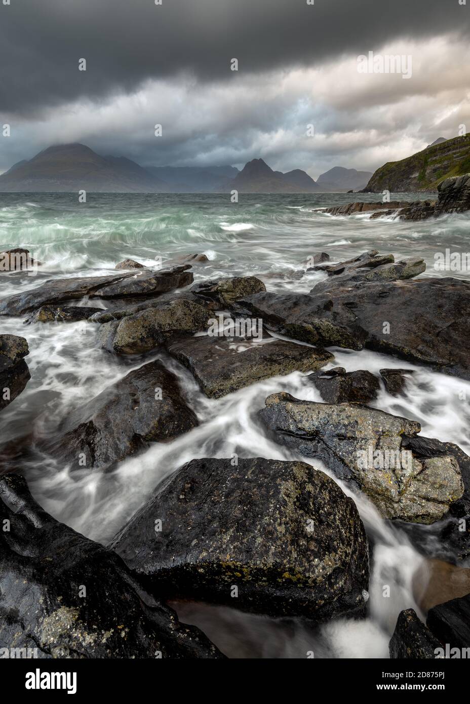 Dramatic Cuillin seascape with dark storm clouds and crashing waves on rocks in foreground. Elgol, Isle of Skye, Scotland, UK. Stock Photo