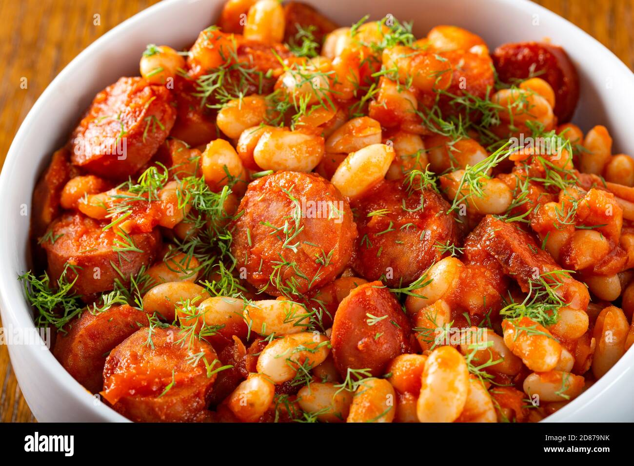 Beans stew with pork sausages and herbs Stock Photo
