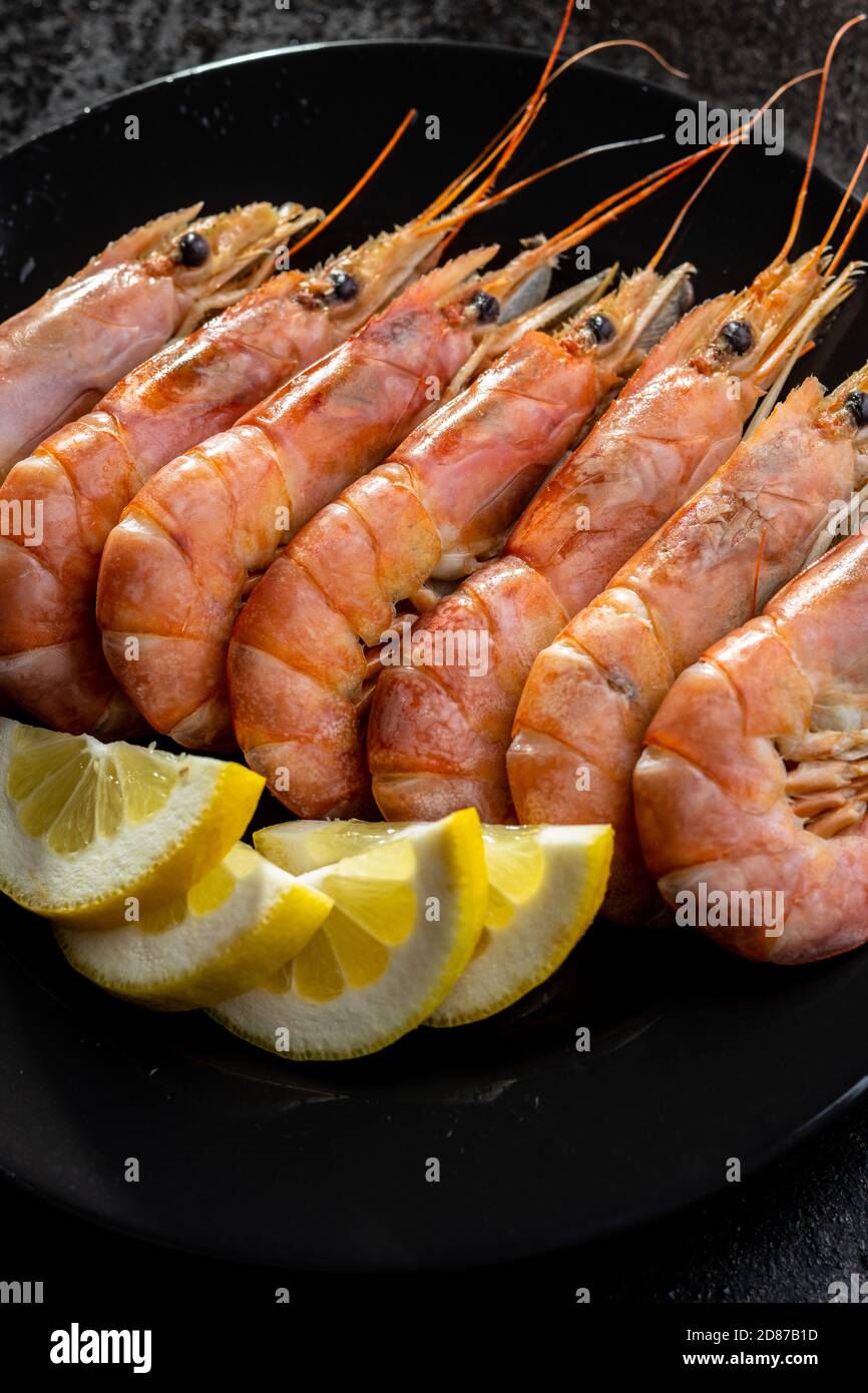 Boiled tiger prawns on black plate. Tasty shrimps. Stock Photo