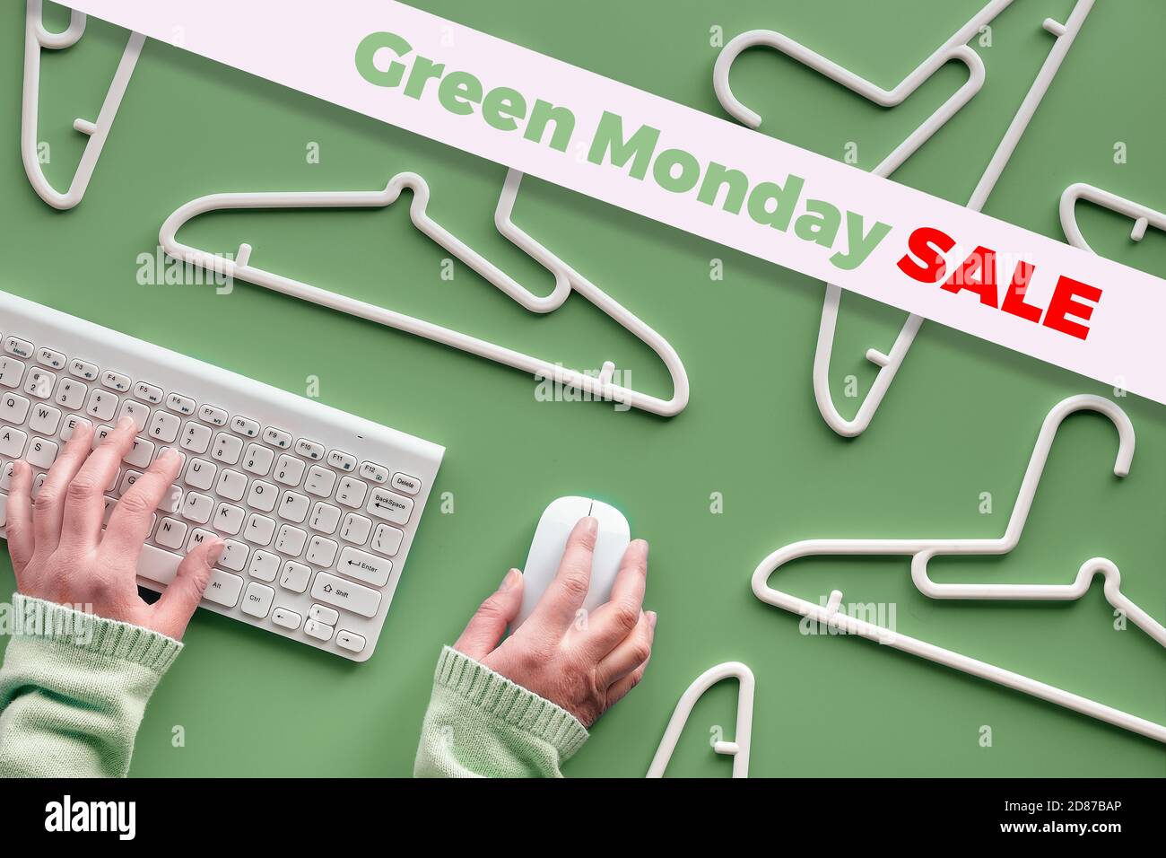 Green Monday sale text on green background with plastic hangers, hands on keyboard and computer mouse Stock Photo