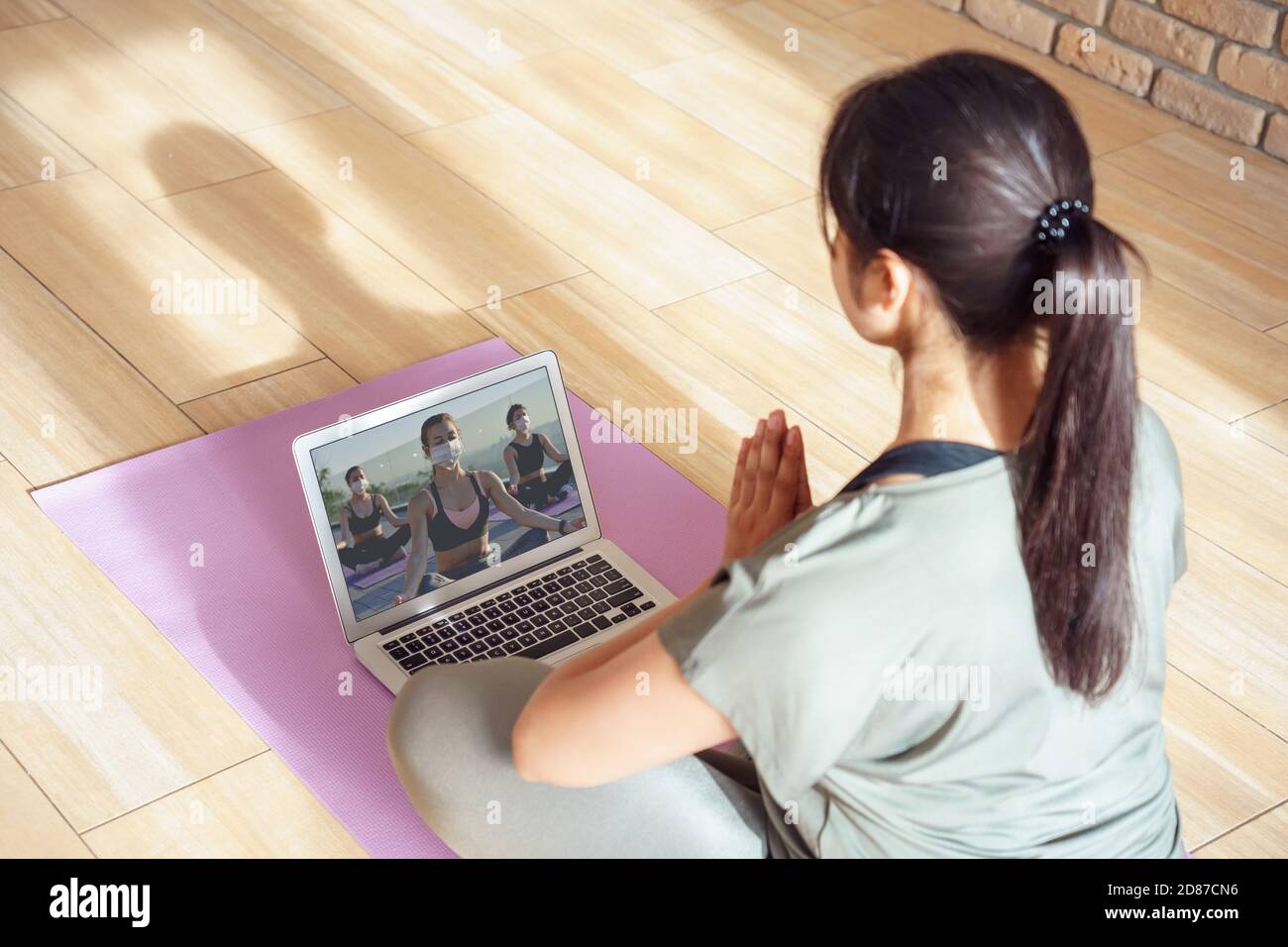 Young woman meditating watching online yoga class video tutorial at home. Stock Photo