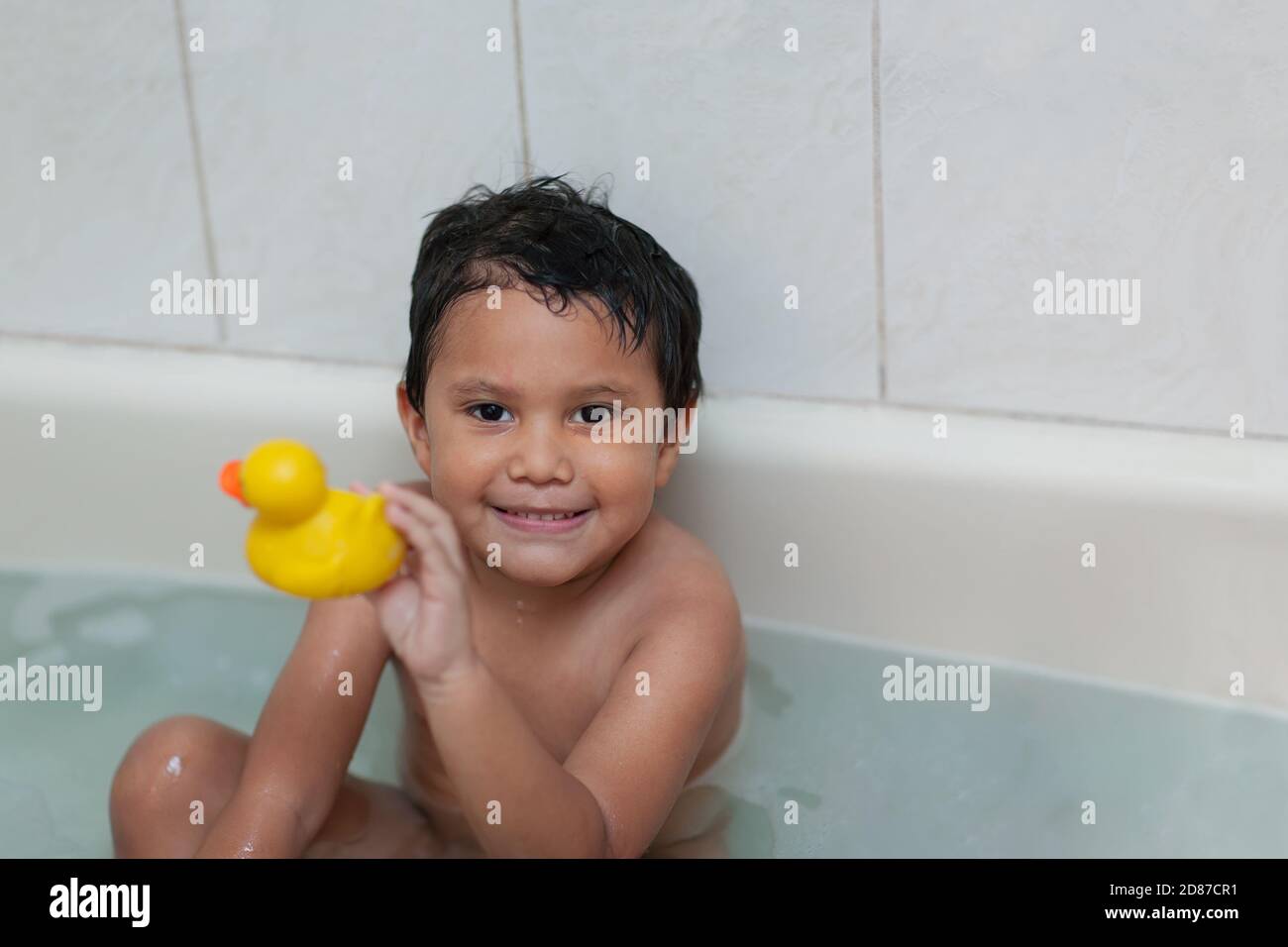 Four year old boy holding his favorite bubble bath toy while taking a bath. Stock Photo