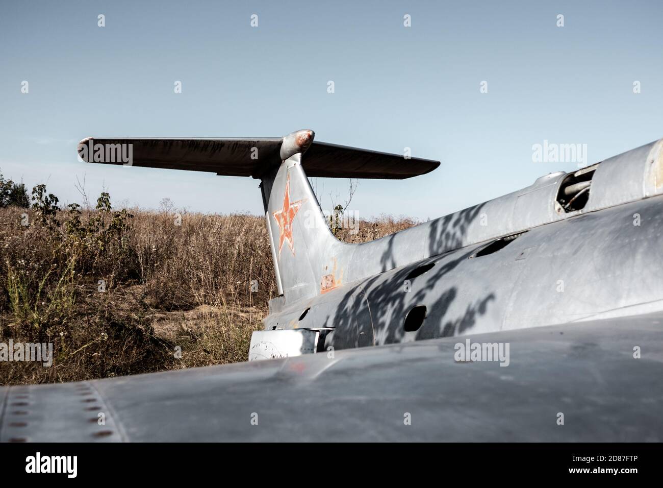 Old soviet plane aluminum grey fuselage and tail empennage view in field. Aero L-29 Delfín a jet-powered trainer aircraft at abandoned Airbase remains Stock Photo