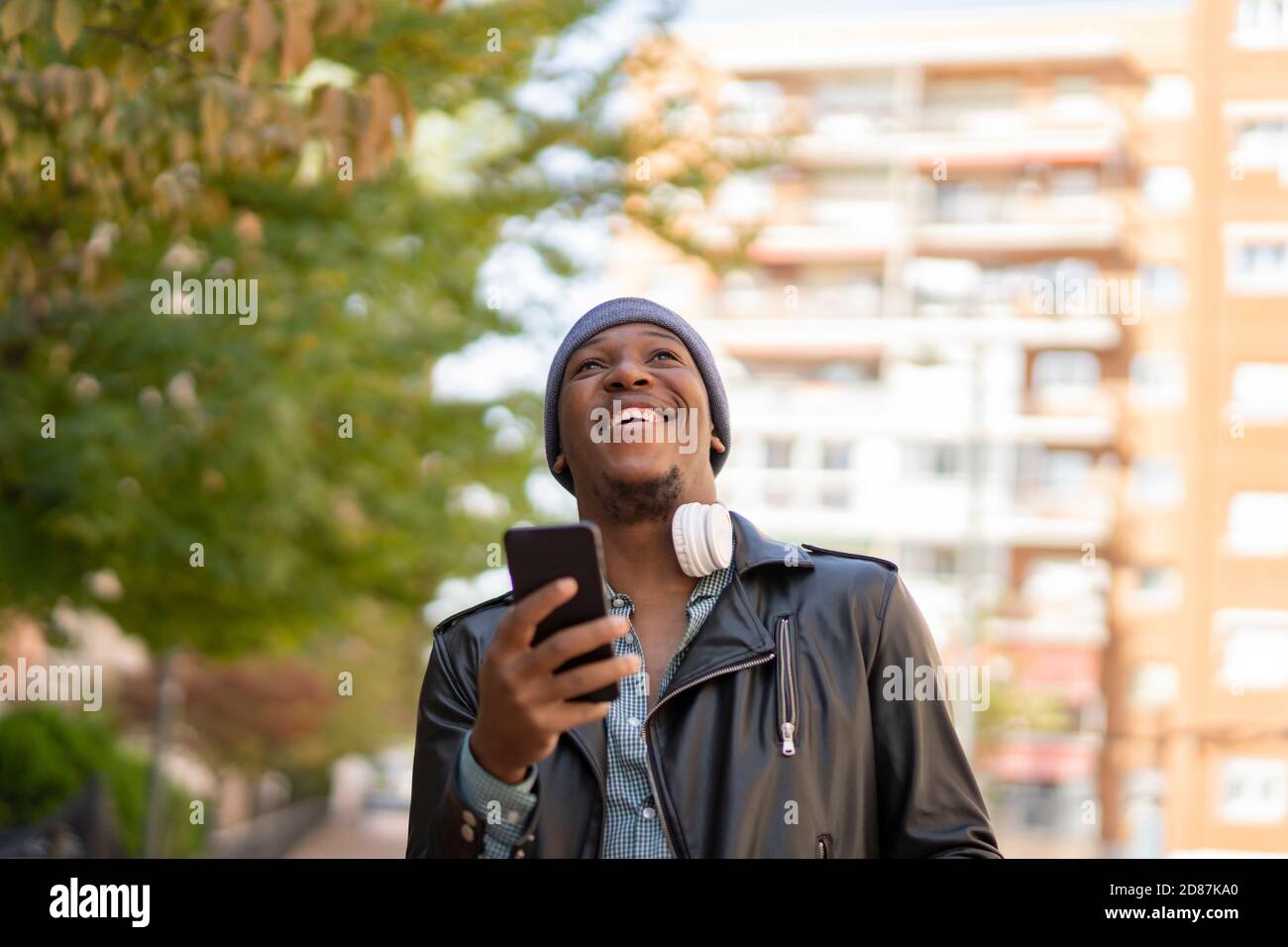 young african man in the city listening to music from his headphones Stock Photo