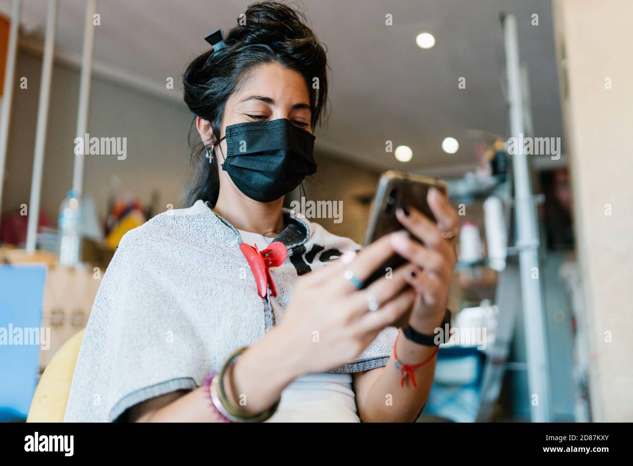 Woman in the hairdresser's with a mask, look at the smart phone Stock Photo Alamy