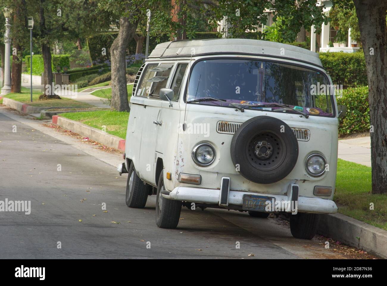 This image shows an old Volkswagen bus parked on a street. Stock Photo