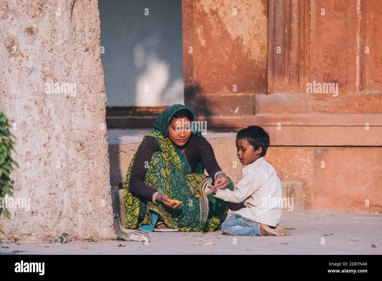 Indian woman and her son feeding a couple squirrels by the Agra fort. Stock Photo