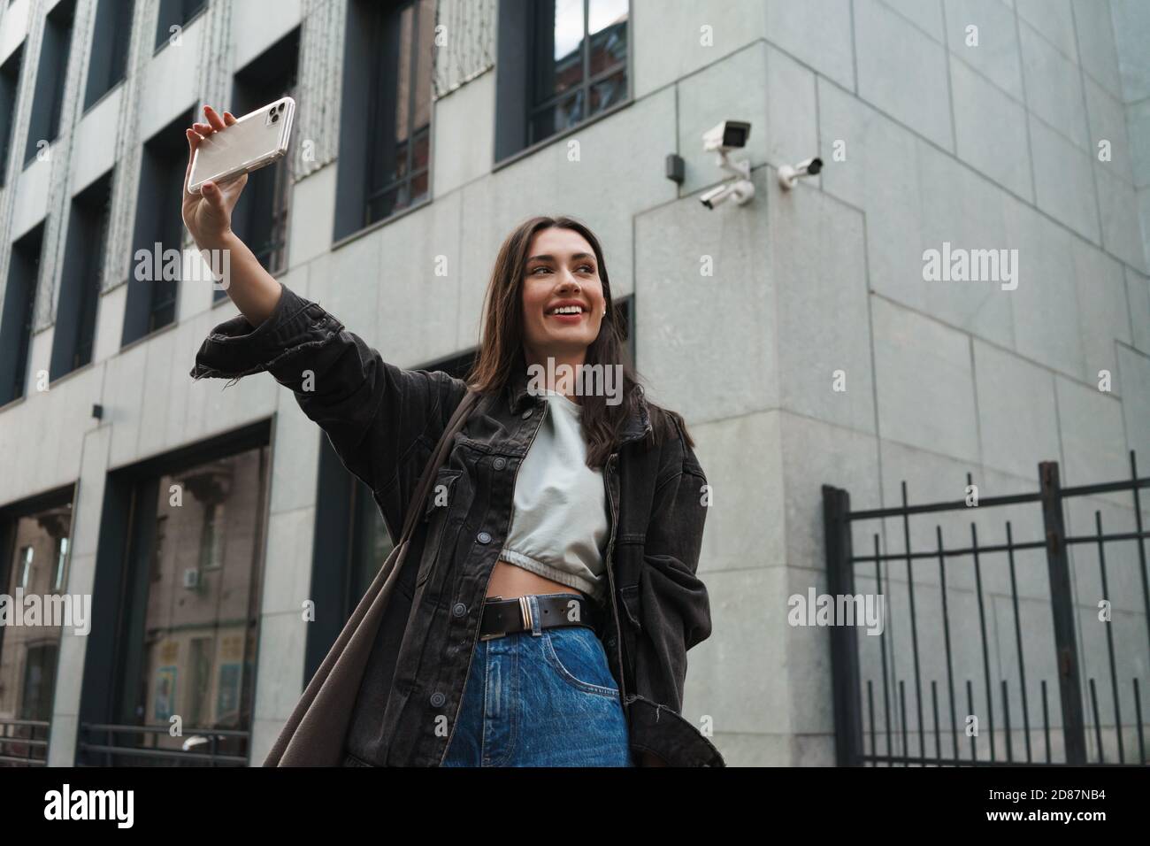 Image of happy cheery young woman walking outdoors by the street and ...