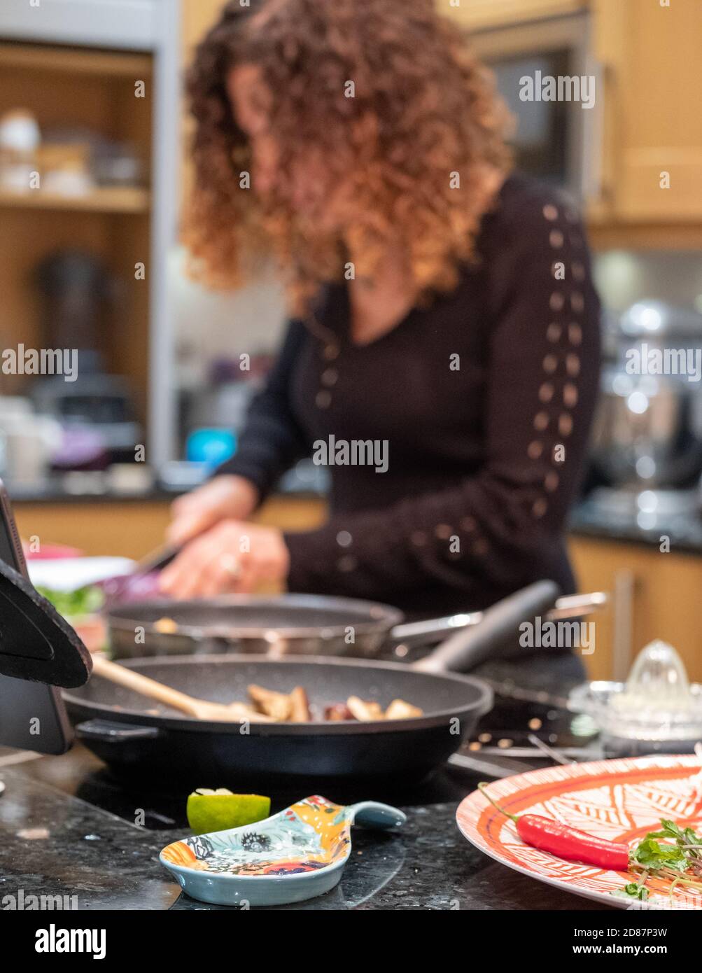Woman preparing a vegan Asian Pad Thai stir fry with red cabbage, aubergine, tofu and noodles. Stock Photo
