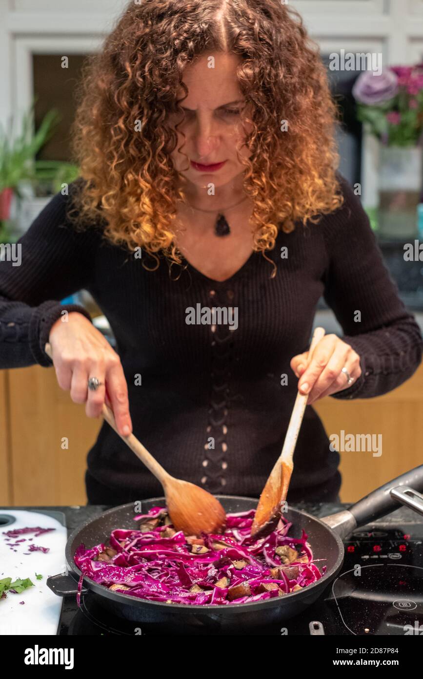 Woman preparing a vegan Asian Pad Thai stir fry with red cabbage, aubergines, tofu and noodles at home. Stock Photo
