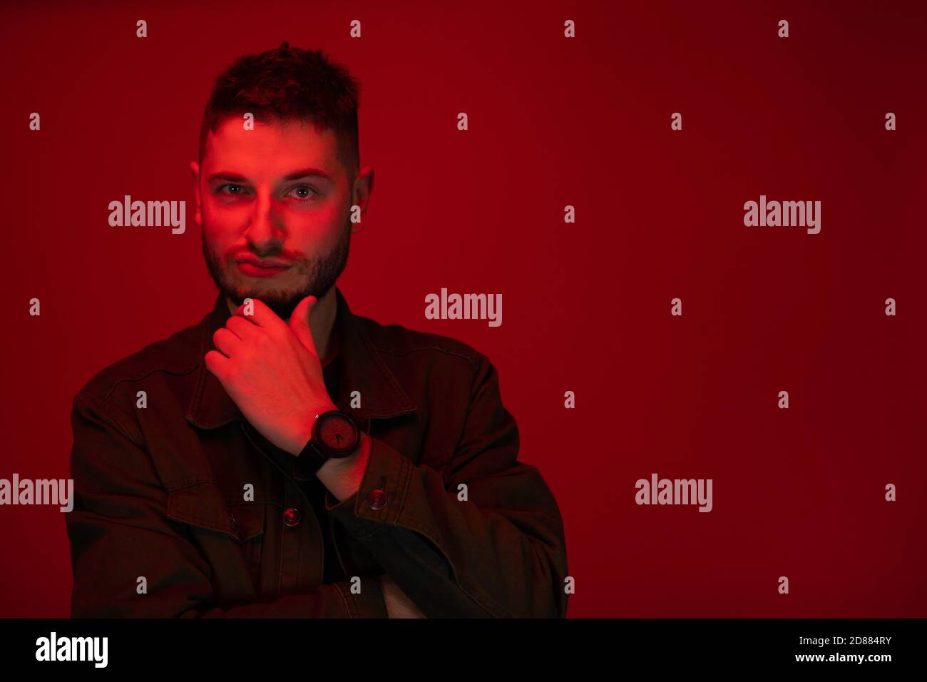 Low key portrait of bearded young man ironic expression in red light