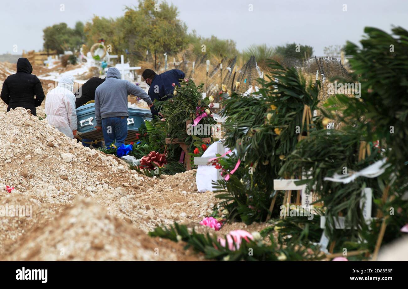 Ciudad Juarez, MEXICO. 27th October, 2020. Cemetery workers bury the bodies of people that were infected with COVID-19 in Ciudad Juarez as a column of smoke rises from the crematory of San Rafael Municipal Cemetery.  COVID-19 victims are buried in a separate part of the cemetery. Today, Mexico reached a total 900,000 cases and almost 90,000 deaths from COVID-19. Credit: Corrie Boudreaux/Alamy Live News Stock Photo