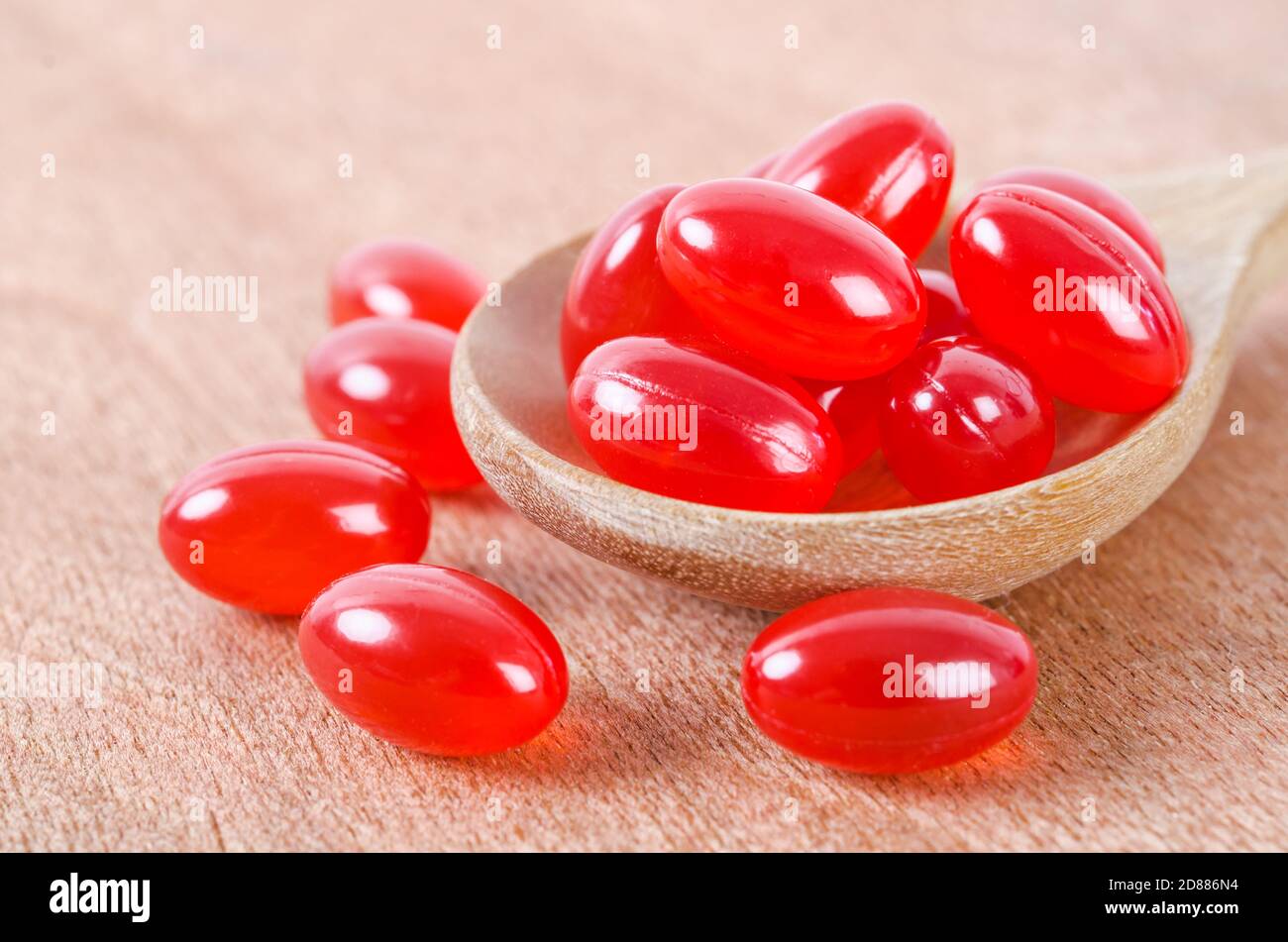 Vitamin Coenzyme Q10 in wooden spoon on wooden background. To prevent aging. Pills and medicine Stock Photo