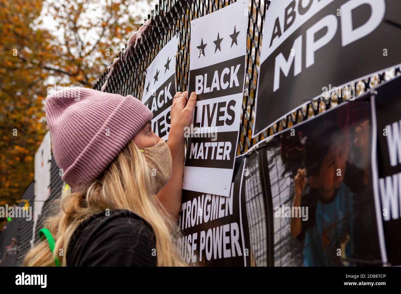 Washington, DC, USA, 27 October, 2020.  Pictured: A woman hangs a Black Lives Matter sign on the Lafayette Square fence during at an event to redecorate the fence with protest art.  Trump supporters destroyed the exist art the night of October 26, 2020, as DC police officers watched.  The fence has been covered with protest art since it went up during protests after George Floyd's death. Credit: Allison Bailey/Alamy Live News Stock Photo