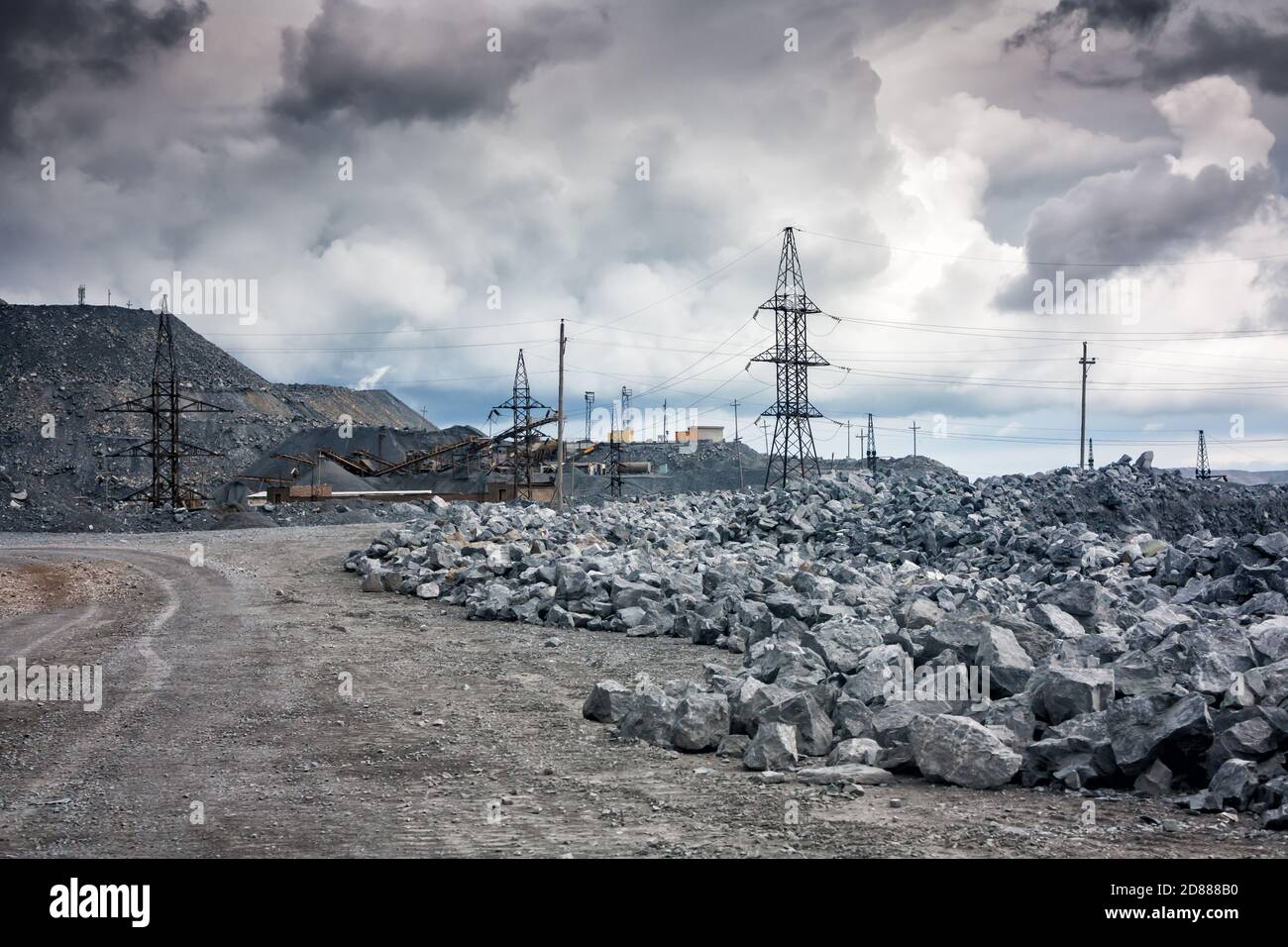 Stone dumps, power lines and crushing machines in a quarry in cloudy weather Stock Photo