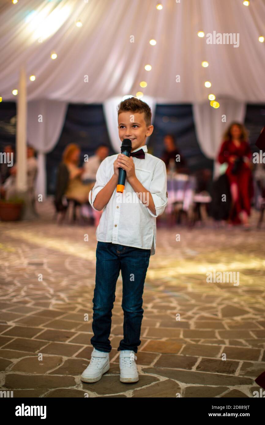 Cute little boy with microphone singing for guests at the holiday Stock Photo