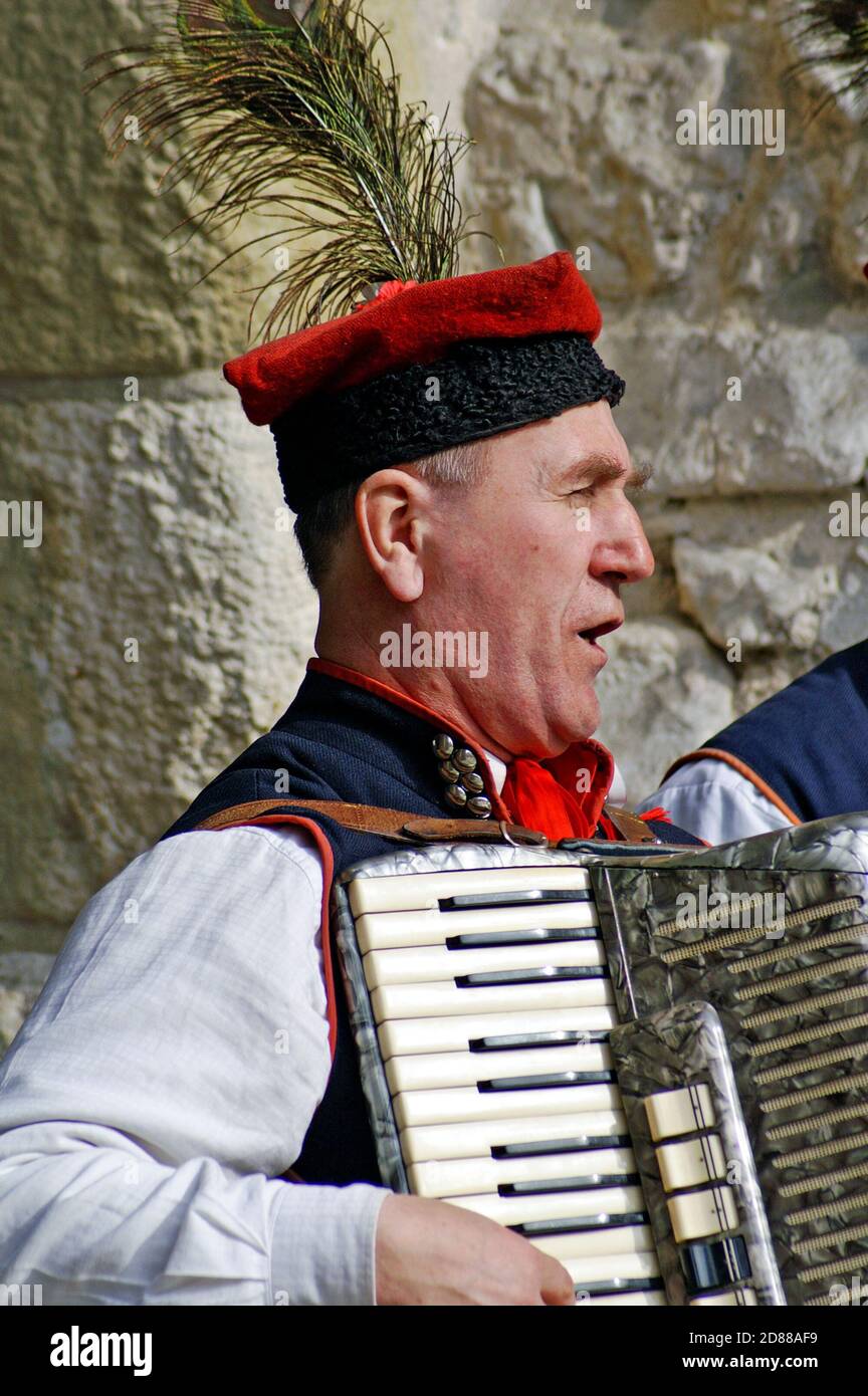 Older Polish man plays the accordian on a street in the Old Town of