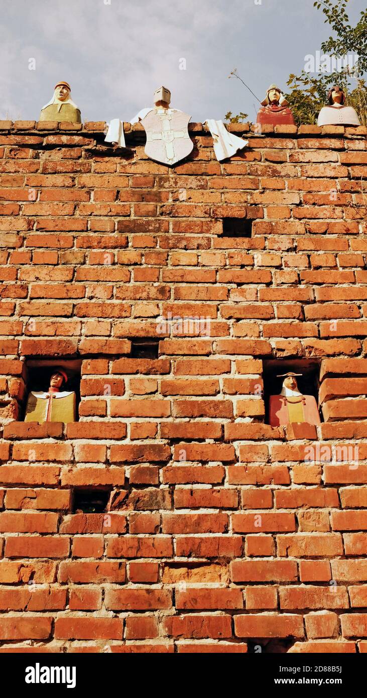 Ceramic busts of medieval burghers sit atop, and in the windows, of a brick wall in the old town of Torun, Poland. Stock Photo