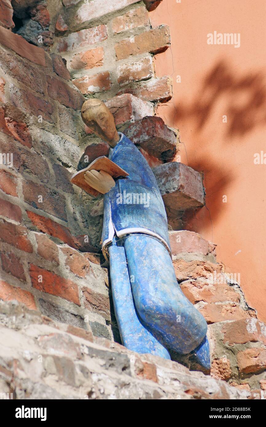 An outdoor ceramic figure of a person reading a book graces one of the old town walls in Torun, Poland.  The sculpture is one of many found in Torun. Stock Photo