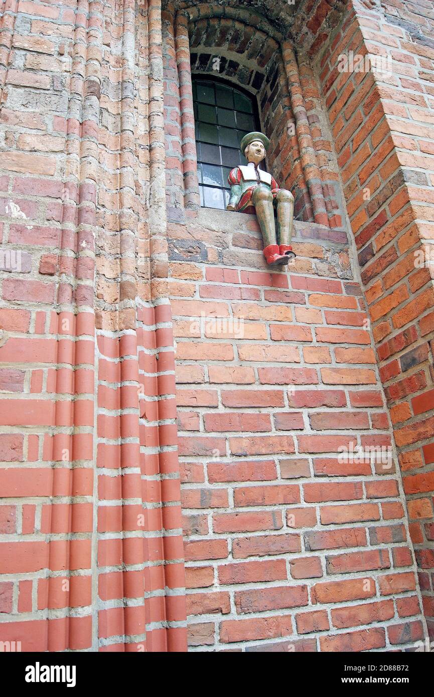 A ceramic medieval burghers perched on the windowsill outside the brick Gothic style Old Town City Hall in Torun, Poland. Stock Photo