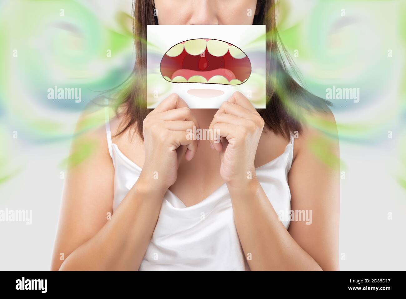 A woman wearing white dress holding a white paper with an open mouth cartoon image. On a light gray background. Bad breath or Halitosis. The concept w Stock Photo