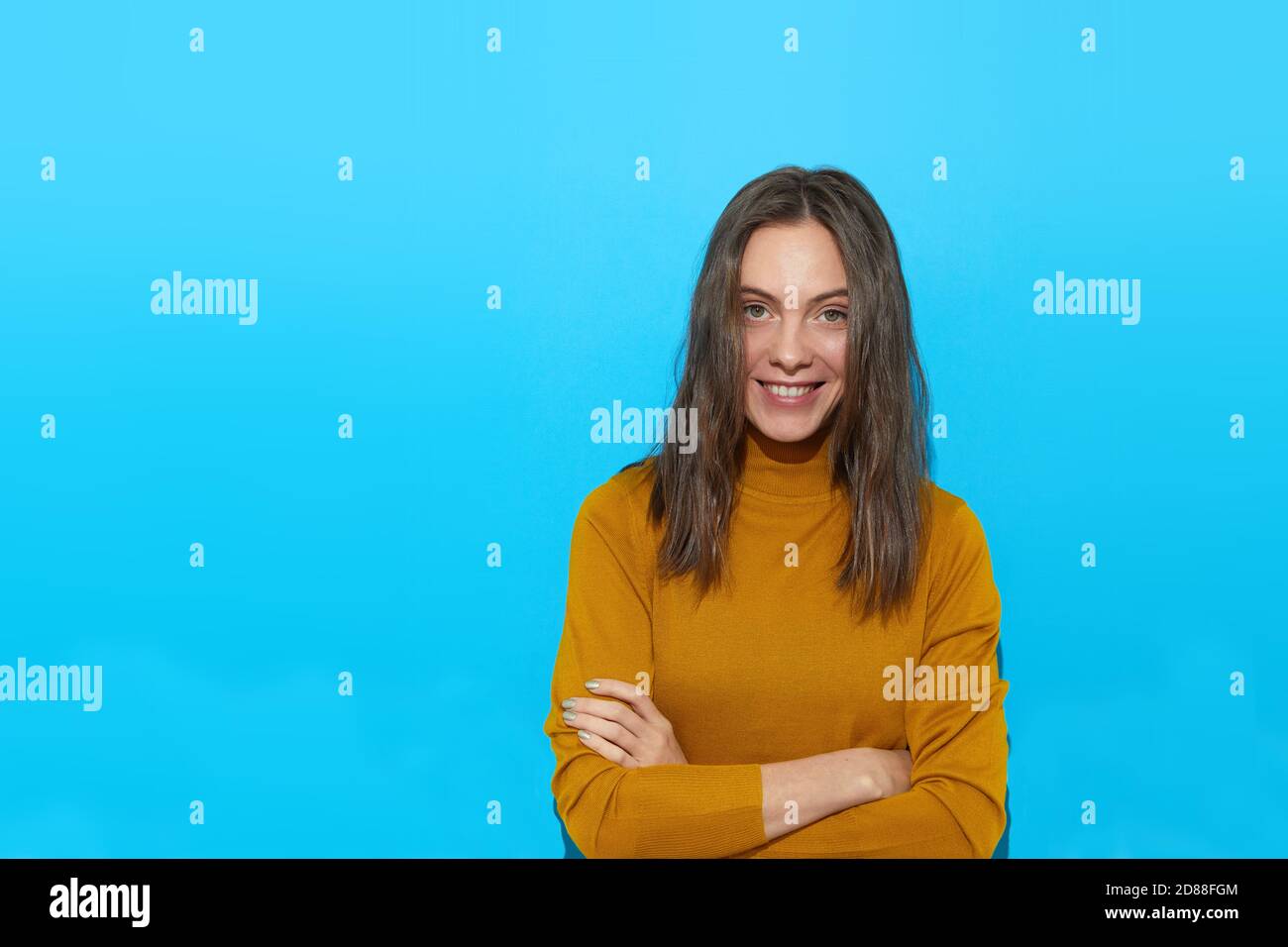 Smiling woman with crossed arms in studio Stock Photo