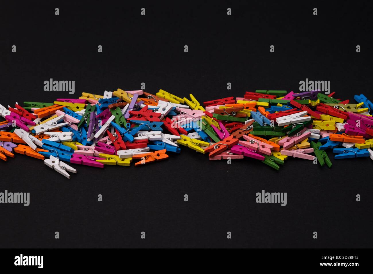 Colored wooden clothes pegs in middle of black background, colorful