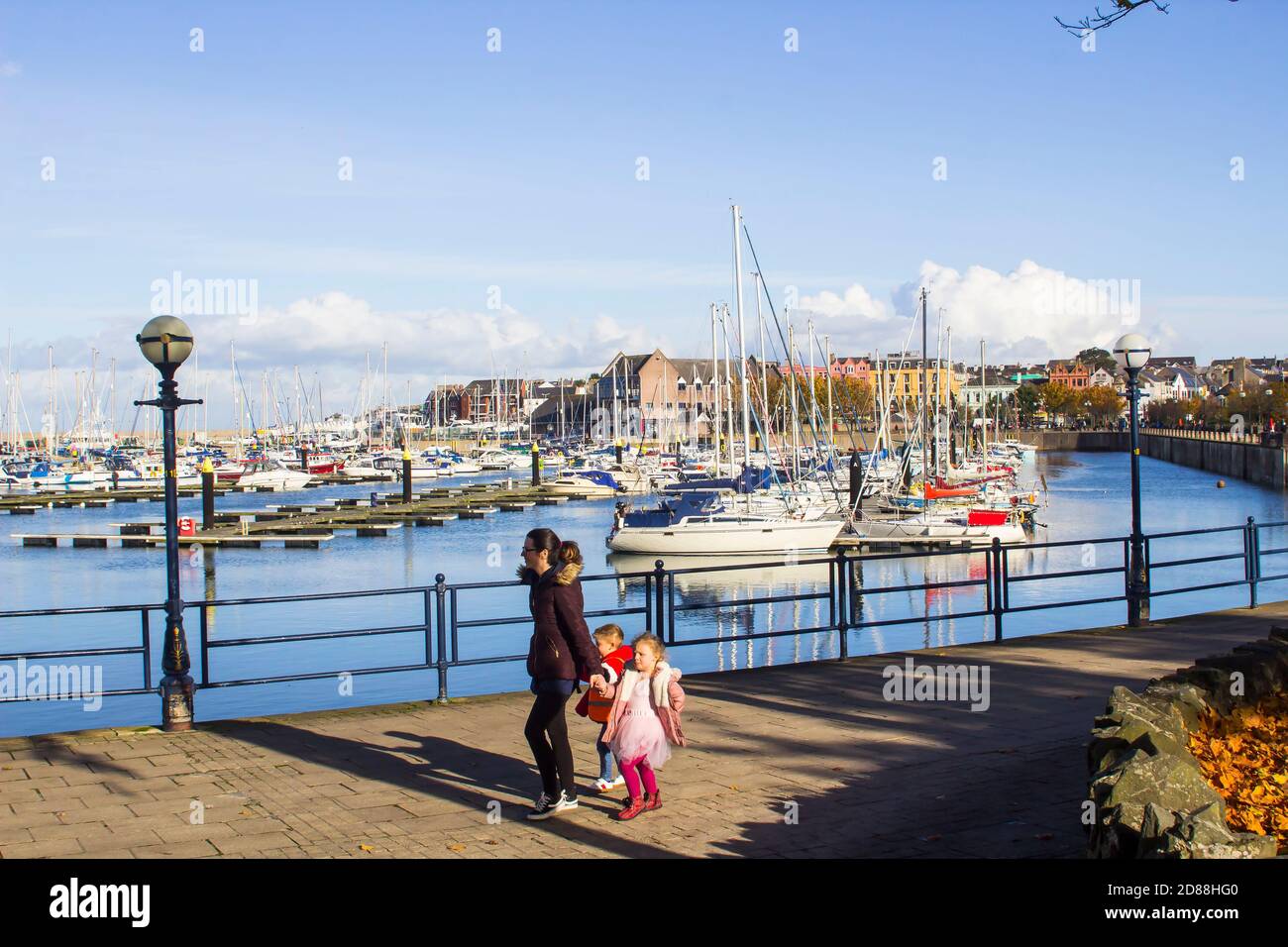 23 October 2020 A mother and children walk the promenade beside the modern marina and its boats in Bangor County Down Northern Ireland on a beautiful Stock Photo