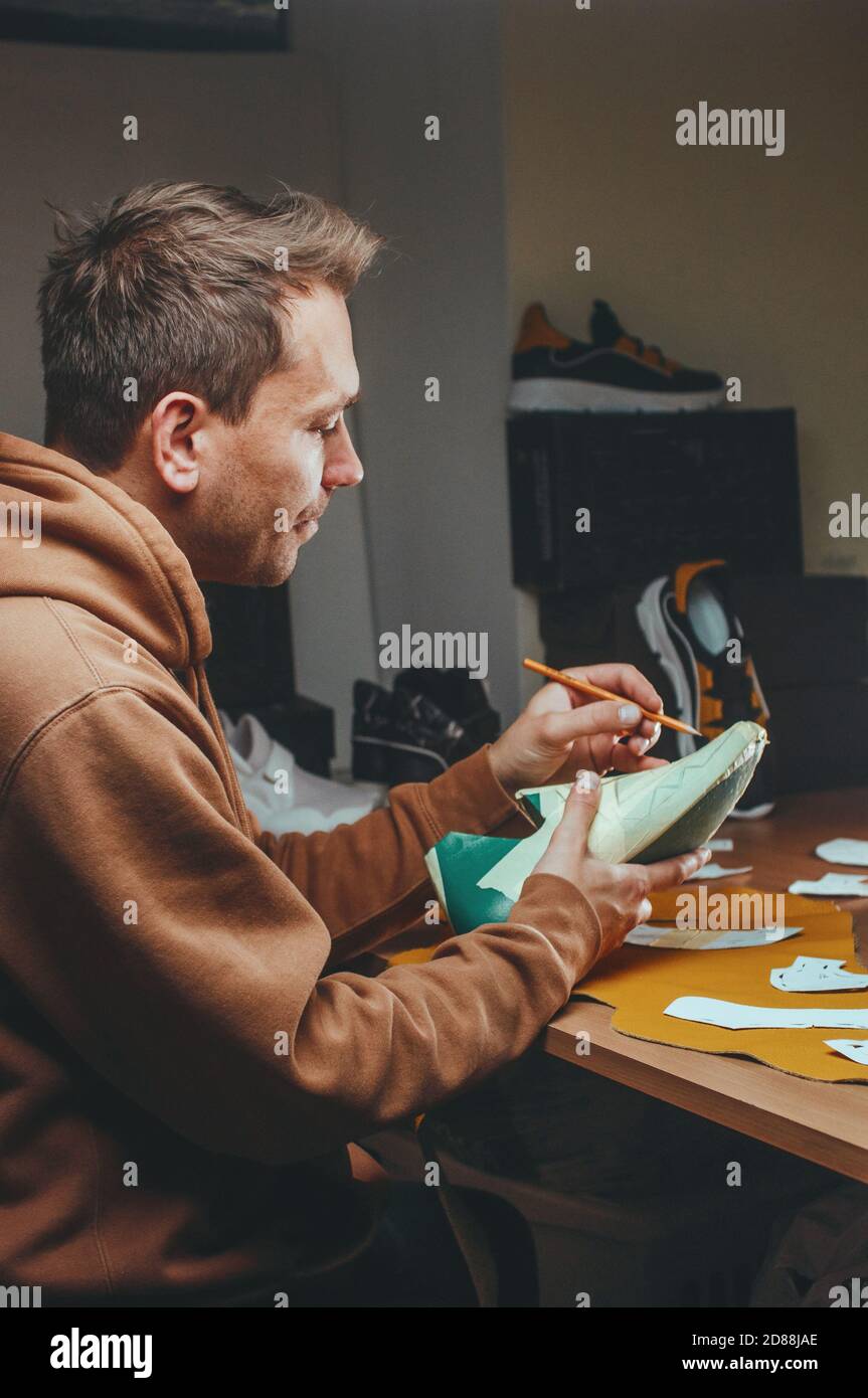Shoemaker cutting patterns using knife from leather Stock Photo