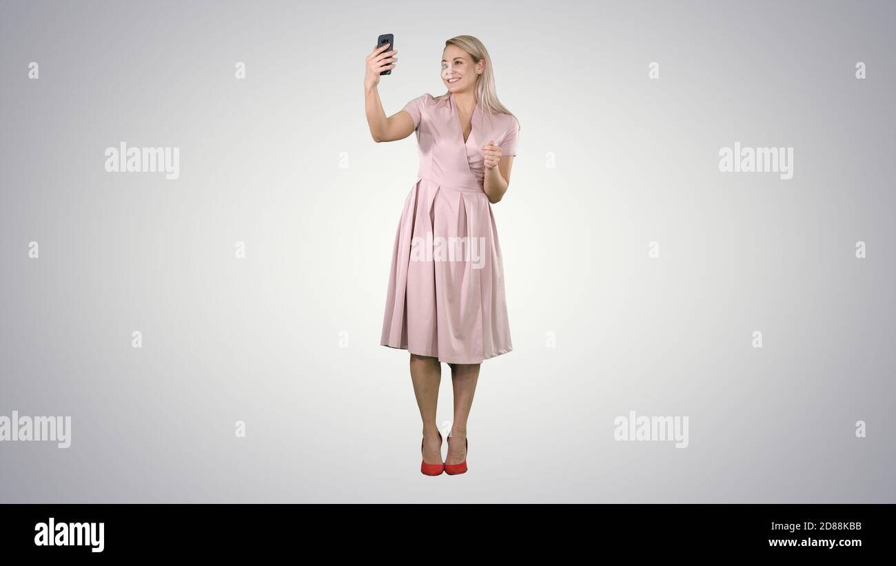 Mature woman wearing light pink dress making selfie on gradient Stock Photo  - Alamy
