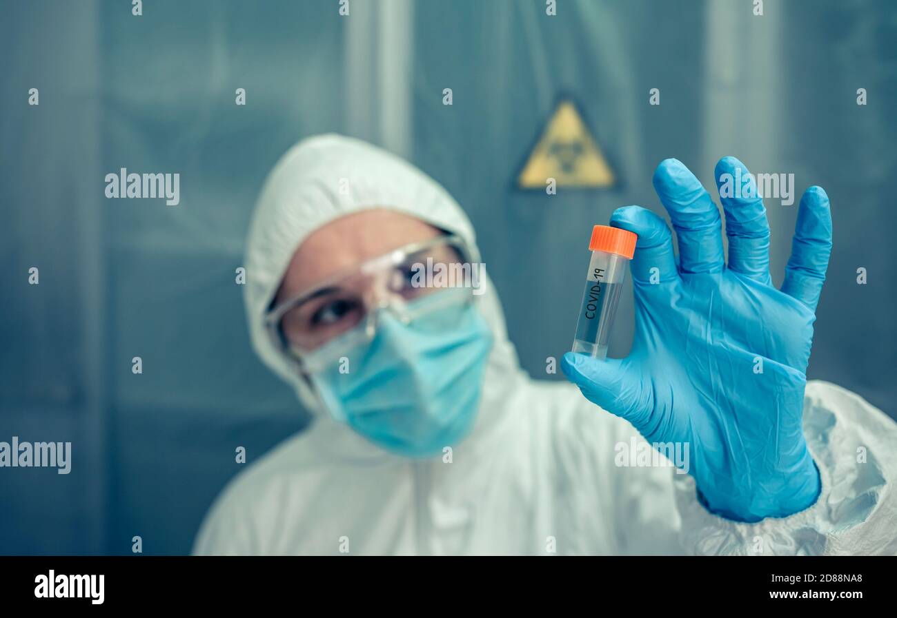 Scientist with protection suit looking vial in the laboratory Stock