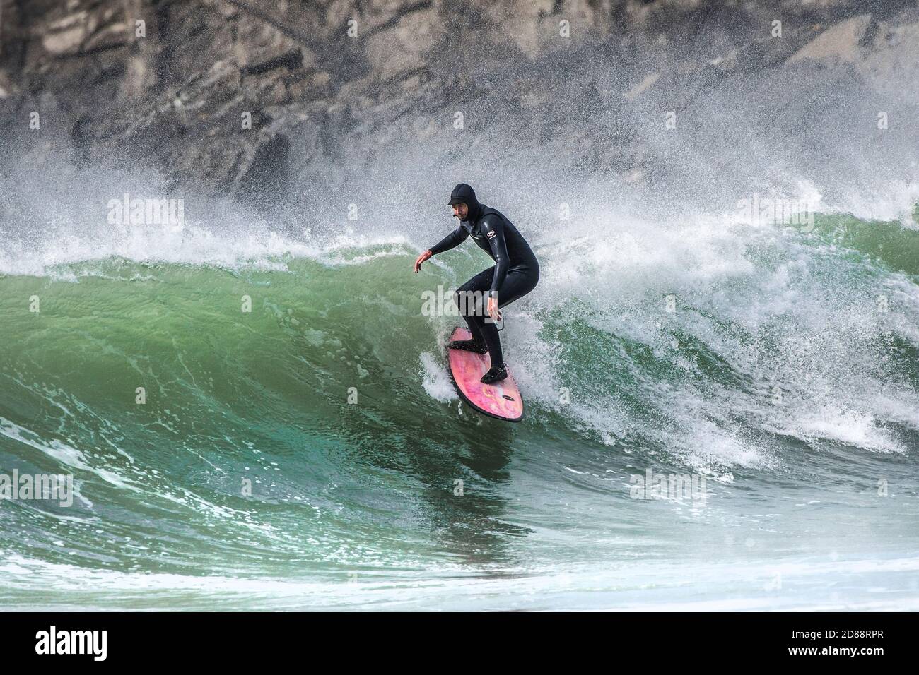 Spectacular action as a determined male surfer rides a wave at Fistral in Newquay in Cornwall. Stock Photo