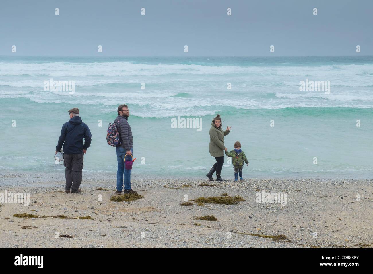 Holidaymakers braving the bad weather on a misty cold day on Fistral Beach in Cornwall. Stock Photo