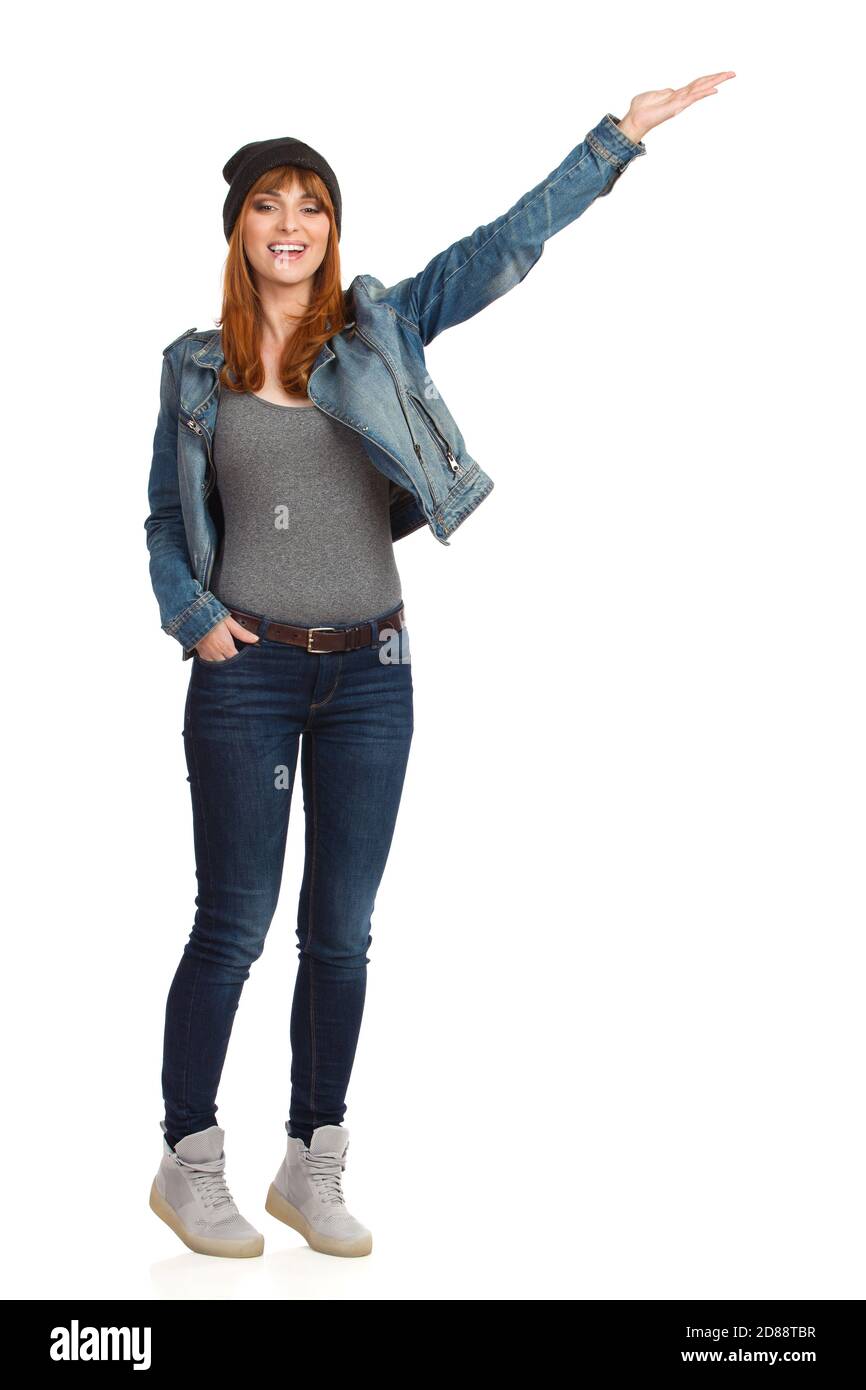 Young woman in unbuttoned jeans jacket, is standing on tiptoes, holding