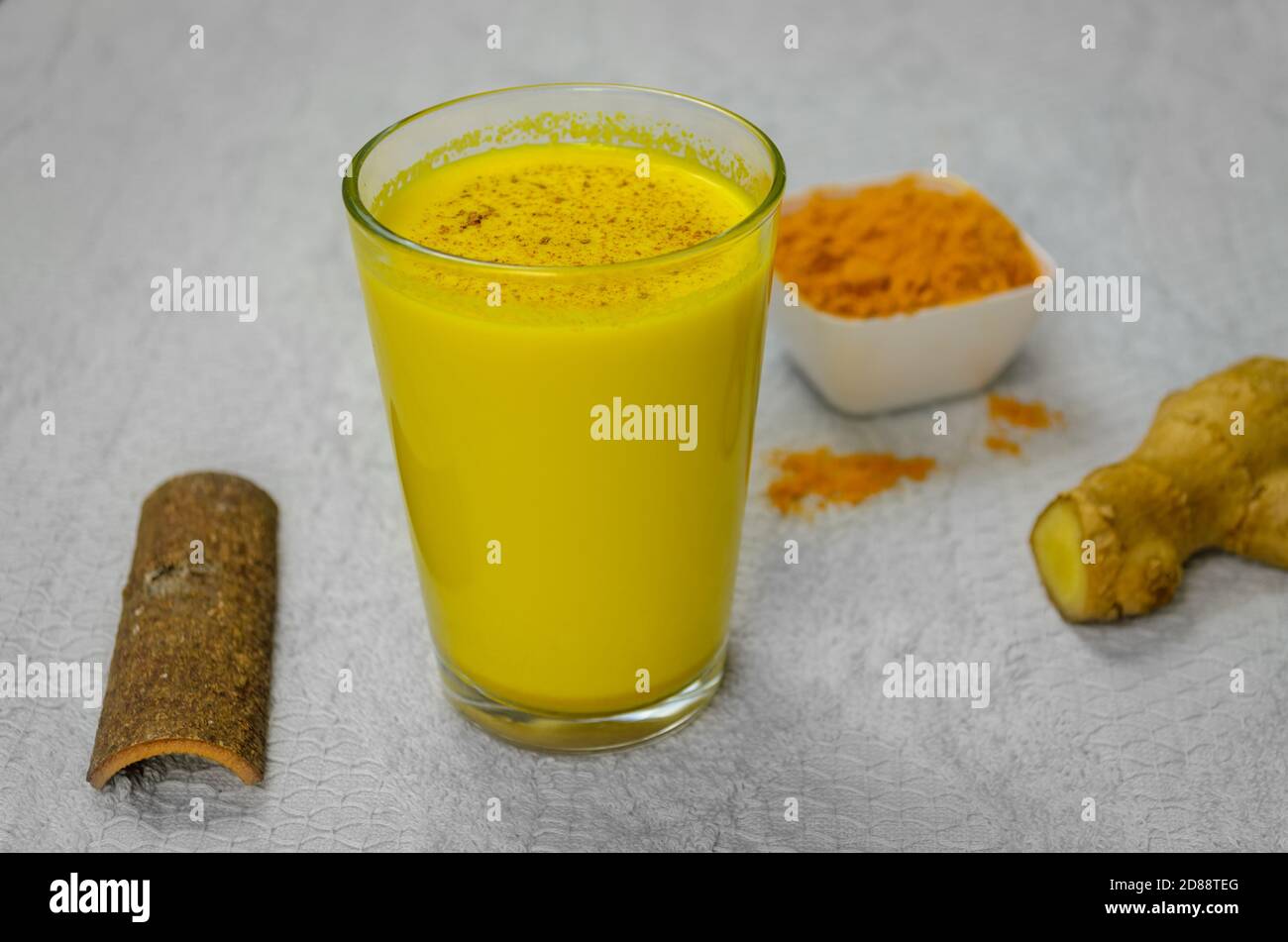 Closeup of Immunity Boosting Turmeric Milk along with cinnamon, turmeric powder and ginger Stock Photo