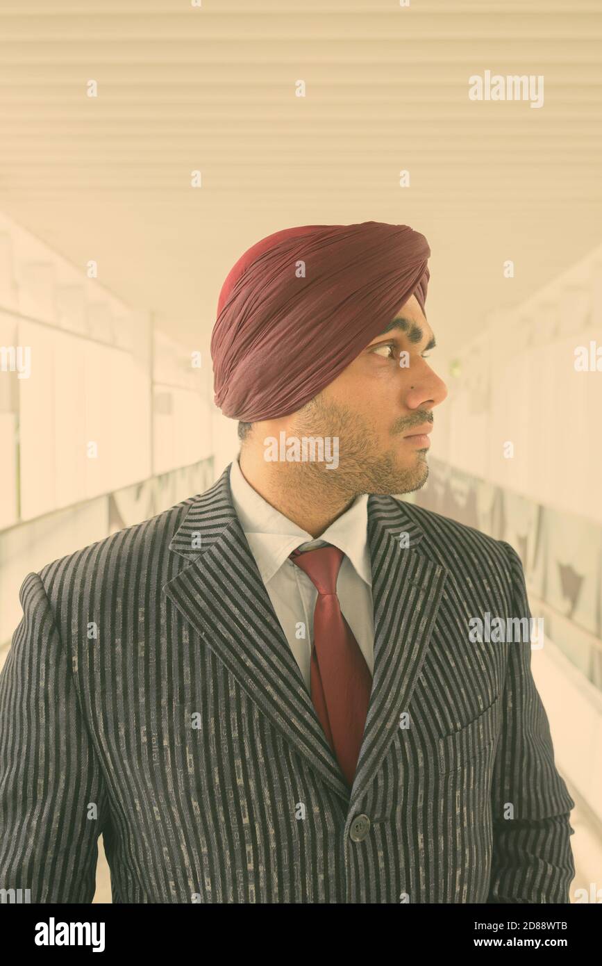 Young handsome Indian Sikh businessman wearing turban while exploring the city Stock Photo