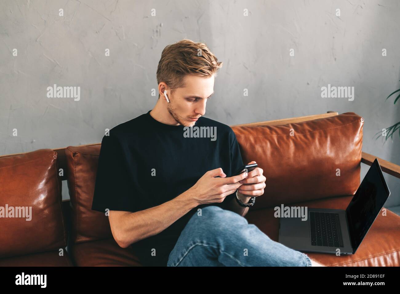 Mman mobile developer in earphones using smartphone, testing application Stock Photo