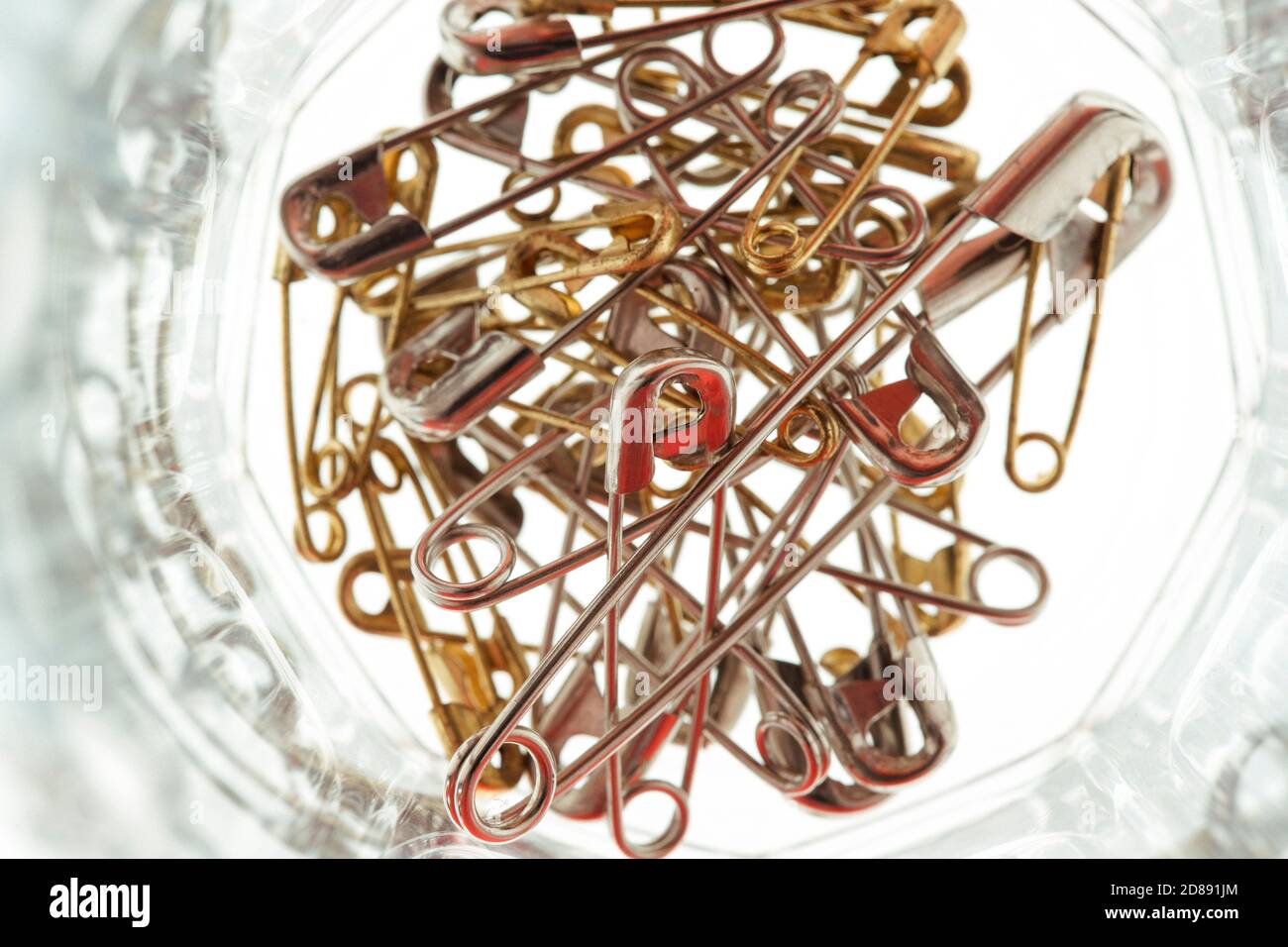 A directly above shot of a pile of metal safety pins in a glass jar