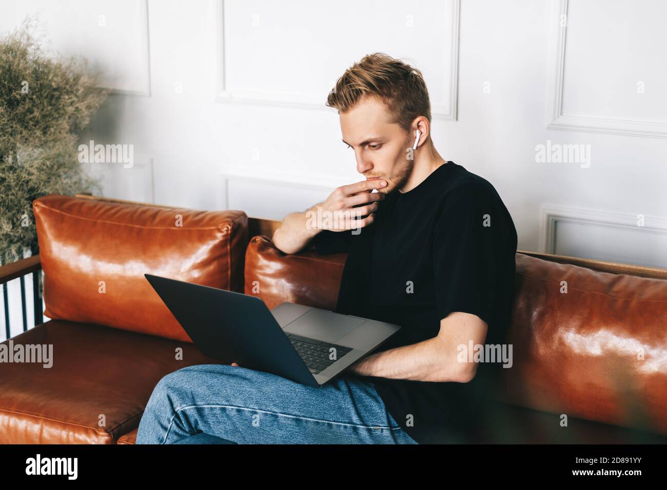 Mobile developer in earphones, programmer writes program code on a laptop Stock Photo