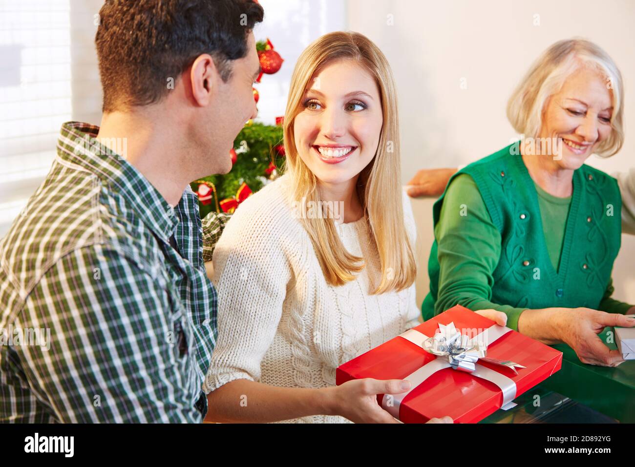 Man gives woman gift at Christmas with family Stock Photo