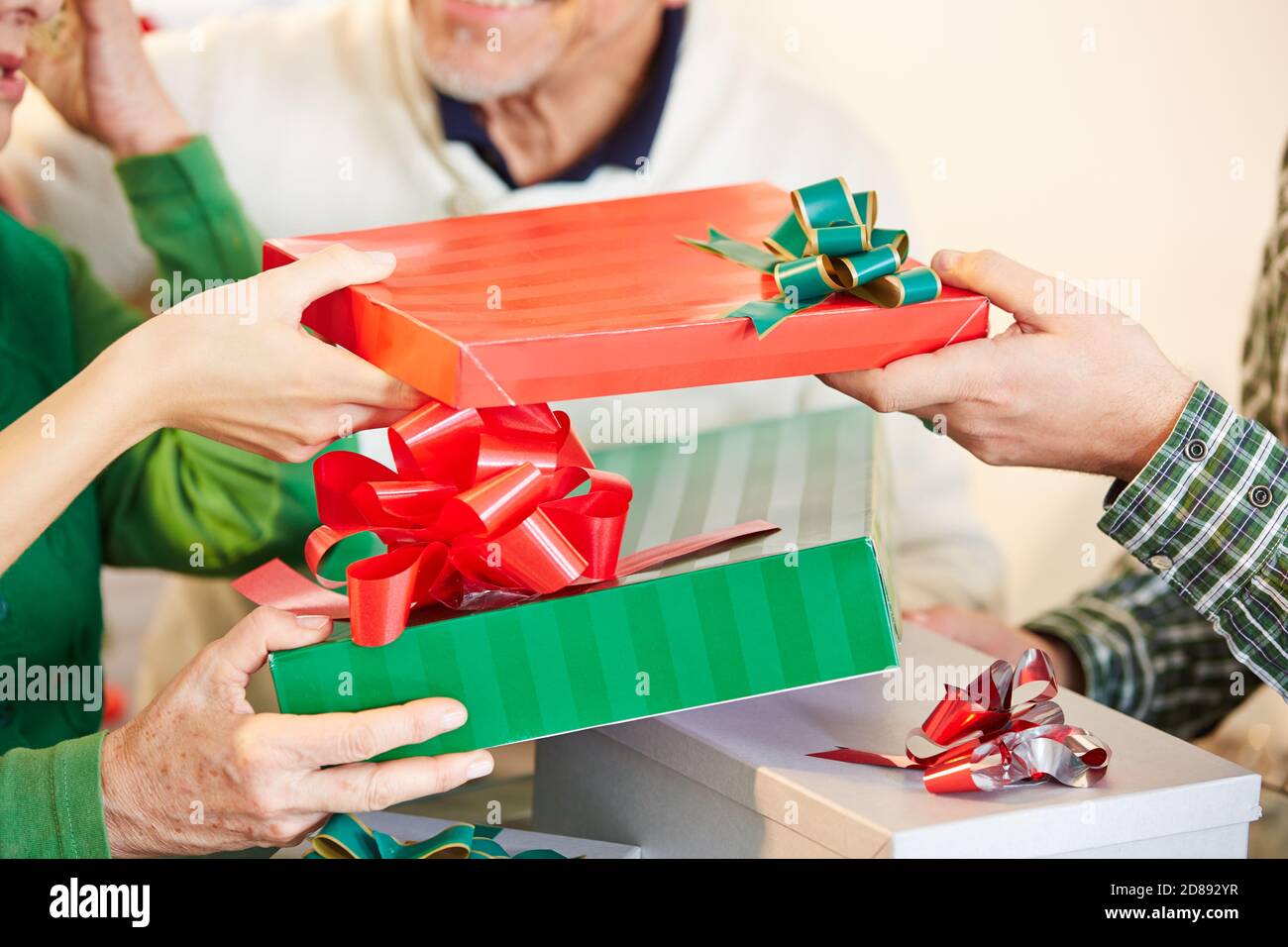 Several hands give wrapped presents for Christmas Stock Photo